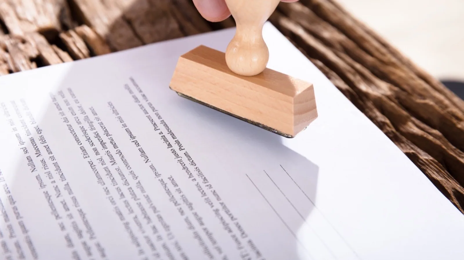 Risikomanagement: Hand setzt einen Stempel auf ein Dokument – Sinnbild für Freigabe und Checkliste im KMU