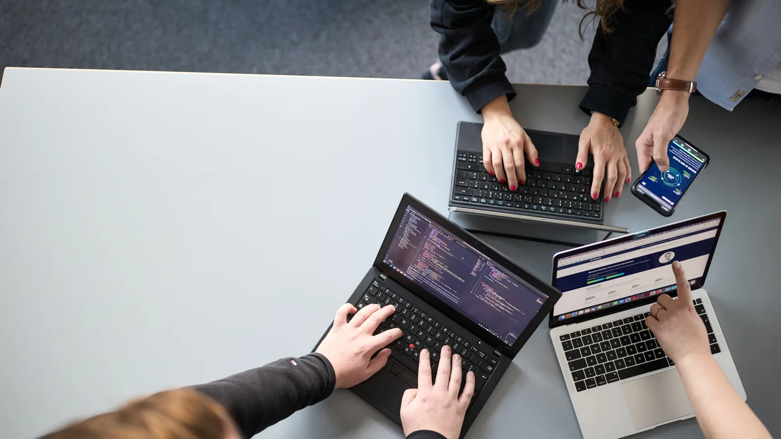 Kubernetes Sicherheit und Compliance: Adacor-Kollegen arbeiten gemeinsam an Laptops an der Konfiguration eines Clusters