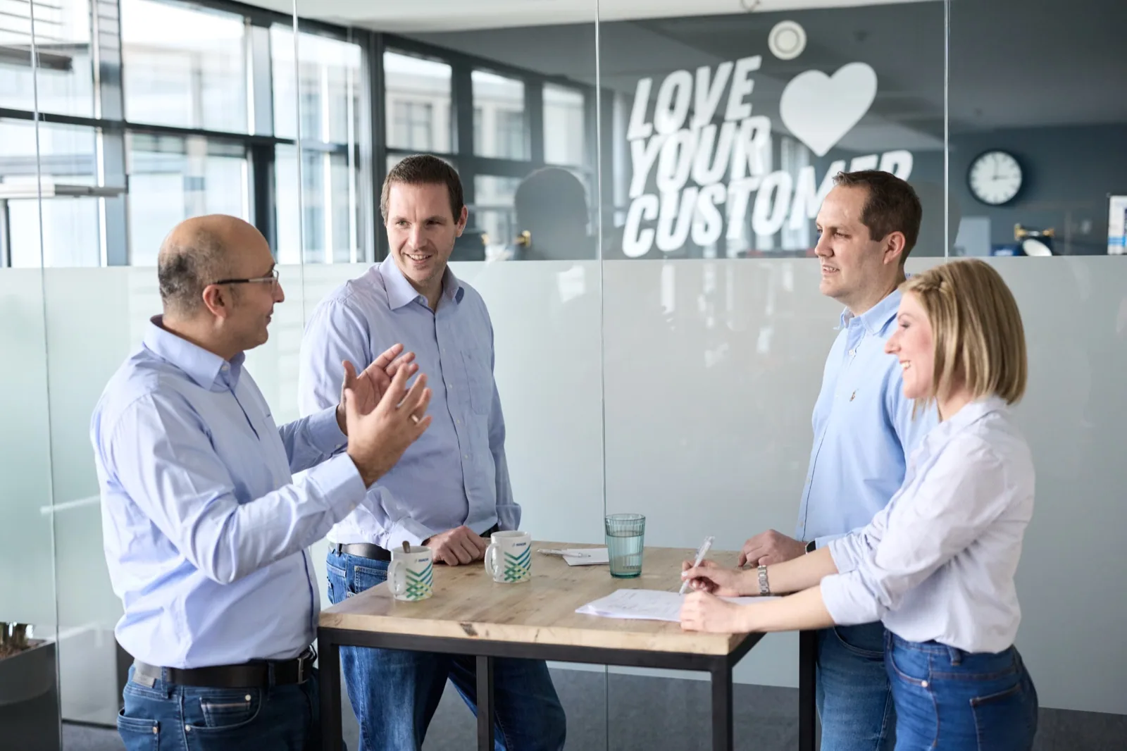 Zusammenarbeit mit Adacor: Team und Kunde im Gespräch am Stehtisch