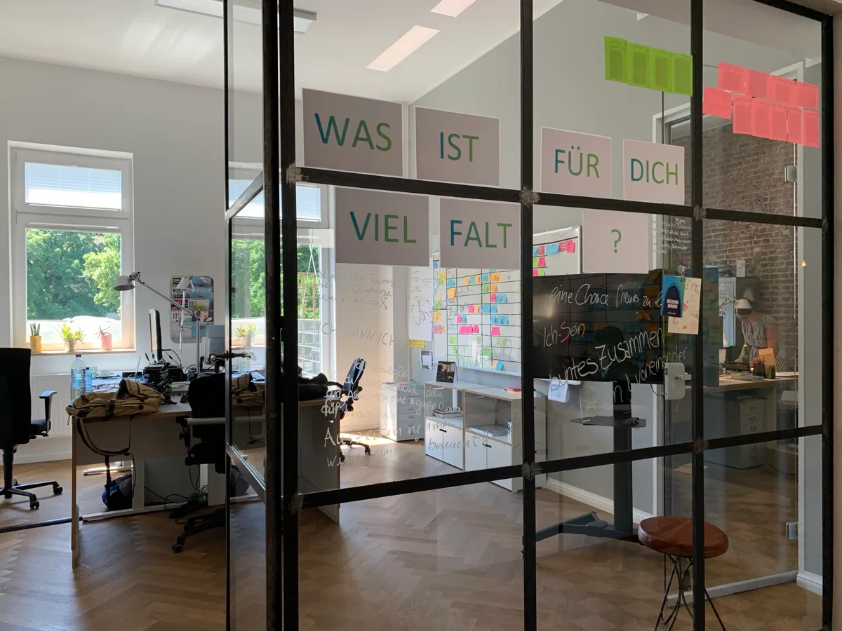 Adacor Standort Essen – Büroeinblick mit Glaswänden und Workshop-Wand