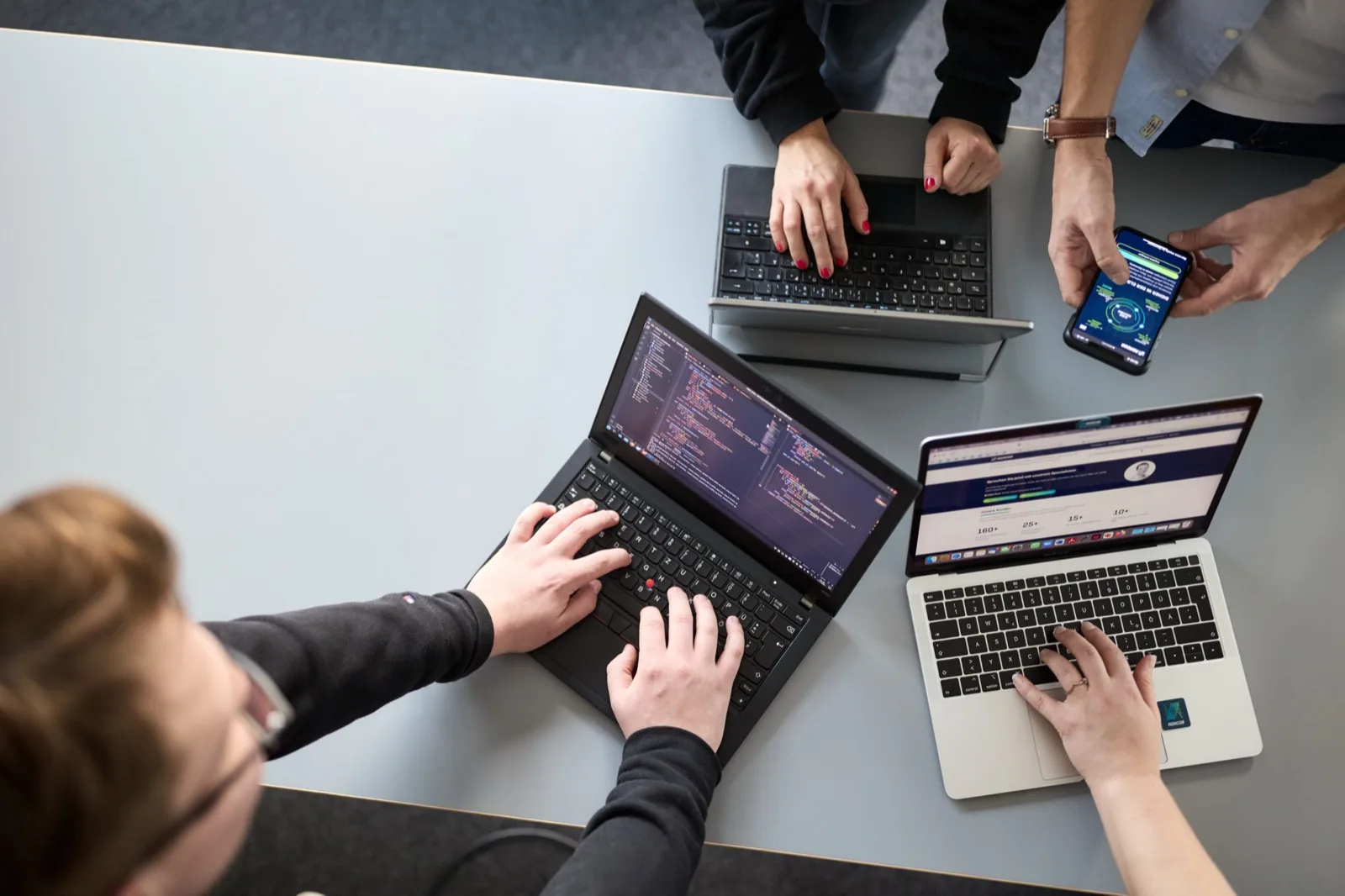 KI-Strategie und Implementierung: Team mit Laptops und Code am Tisch